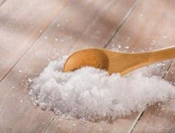 Pile of Epsom Salts on a timber background with a wooden spoon sitting amongst it.