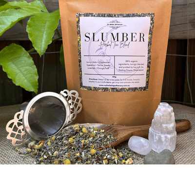 Slumber Organic Herbal Tea Blend crafted by hand for sleep and calm sits on a hessian floor with a leafy background.