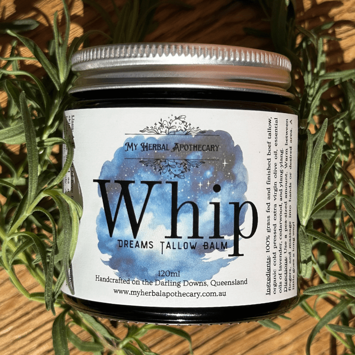 Whip Dreams Tallow Balm 120ml A jar of Whip Dreams Tallow Balm by My Herbal Apothecary sits surrounded by fresh sprigs of greenery, likely lavender. The label features a dreamy night-sky design with stars and a blue-purple watercolor background. Text on the label reads: “Whip Dreams Tallow Balm,” “120ml,” and “Handcrafted on the Darling Downs, Queensland.” The ingredients and website are also listed on the right side of the label.