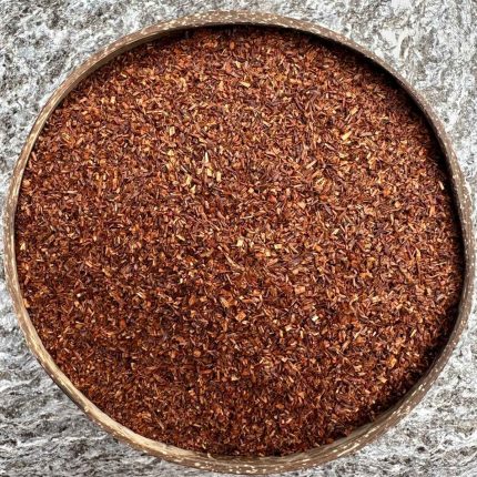 Organic rooibos loose leaf tea in a coconut bowl on a stone background.