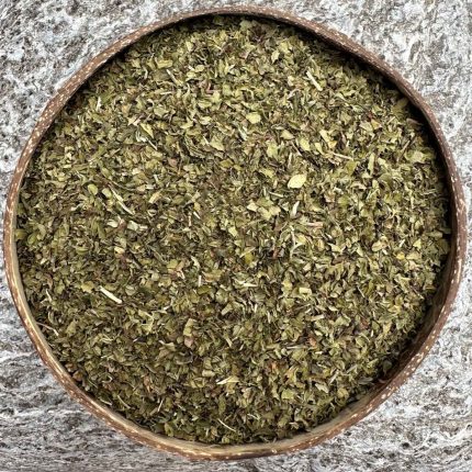 Organic spearmint dried leaf sitting in a coconut bowl on a stone background.