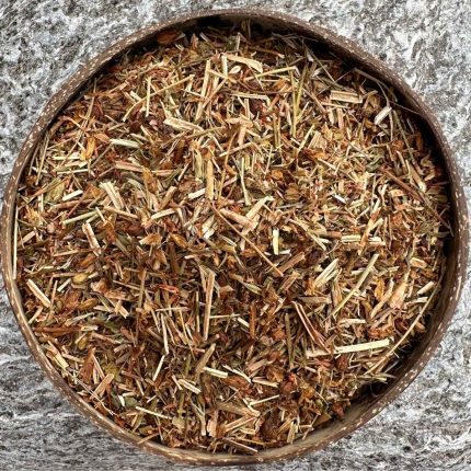 Organic St John’s Wort dried herb sitting in a coconut bowl on a stone background.