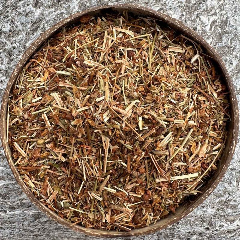 Organic St John’s Wort dried herb sitting in a coconut bowl on a stone background.