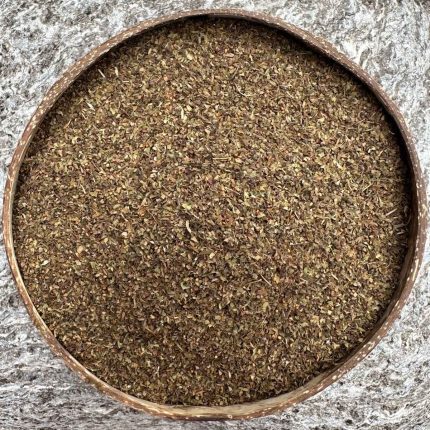 Organic dried Tulsi Holy Basil leaves sitting in a coconut bowl with a stone background.